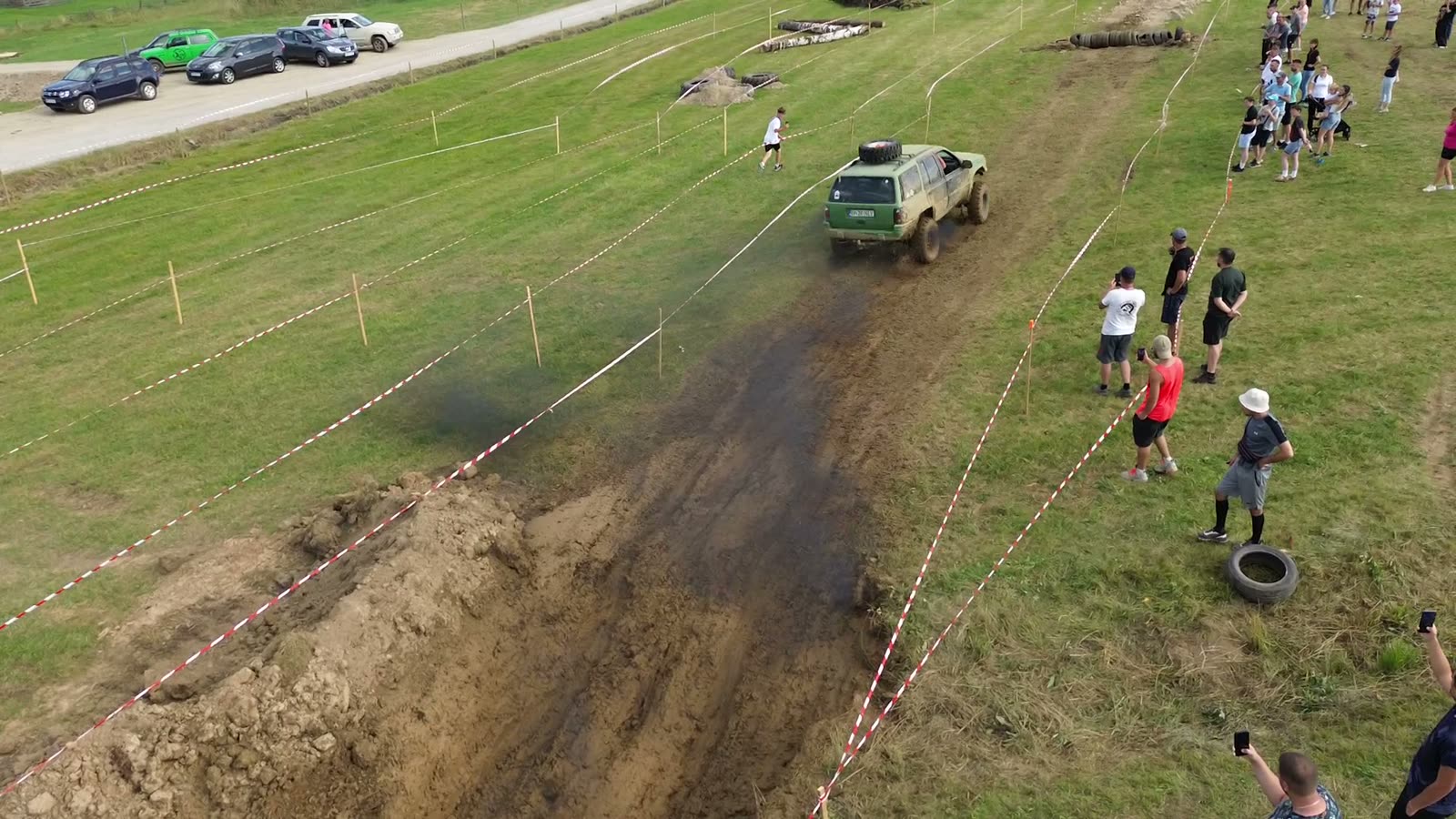 Mașină 4x4 pe pista de noroi de la Bilbor Offroad Fest, cu public de-a lungul benzii roșu-albe